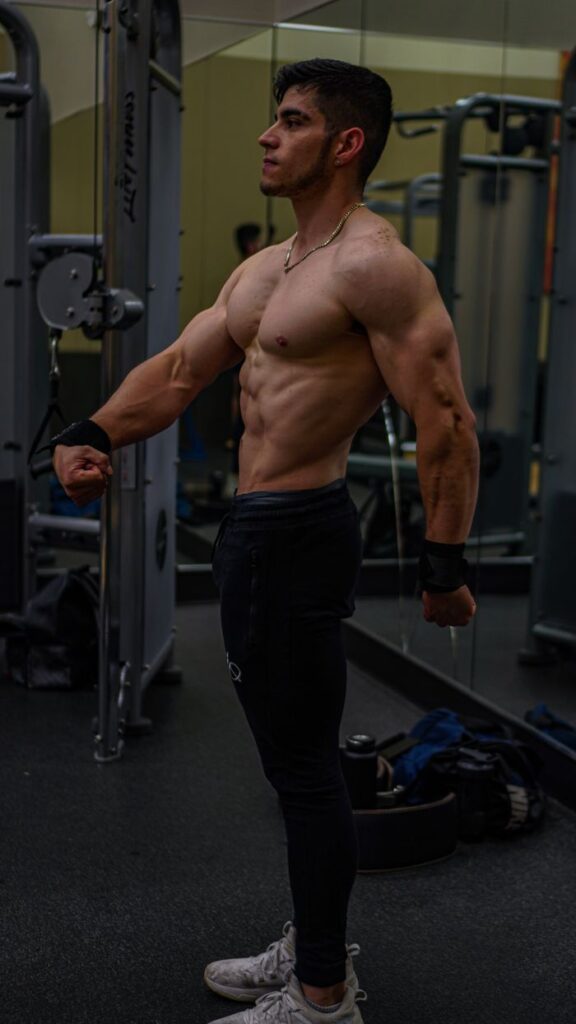 Muscular man flexing his muscles in a gym setting, showcasing strength and fitness.