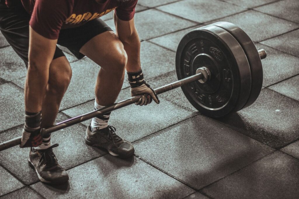 A focused weightlifter prepares to lift a heavy barbell in an indoor gym setting.